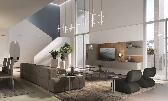 Double-height living room with a grey sofa, sculptural armchairs and a wall unit