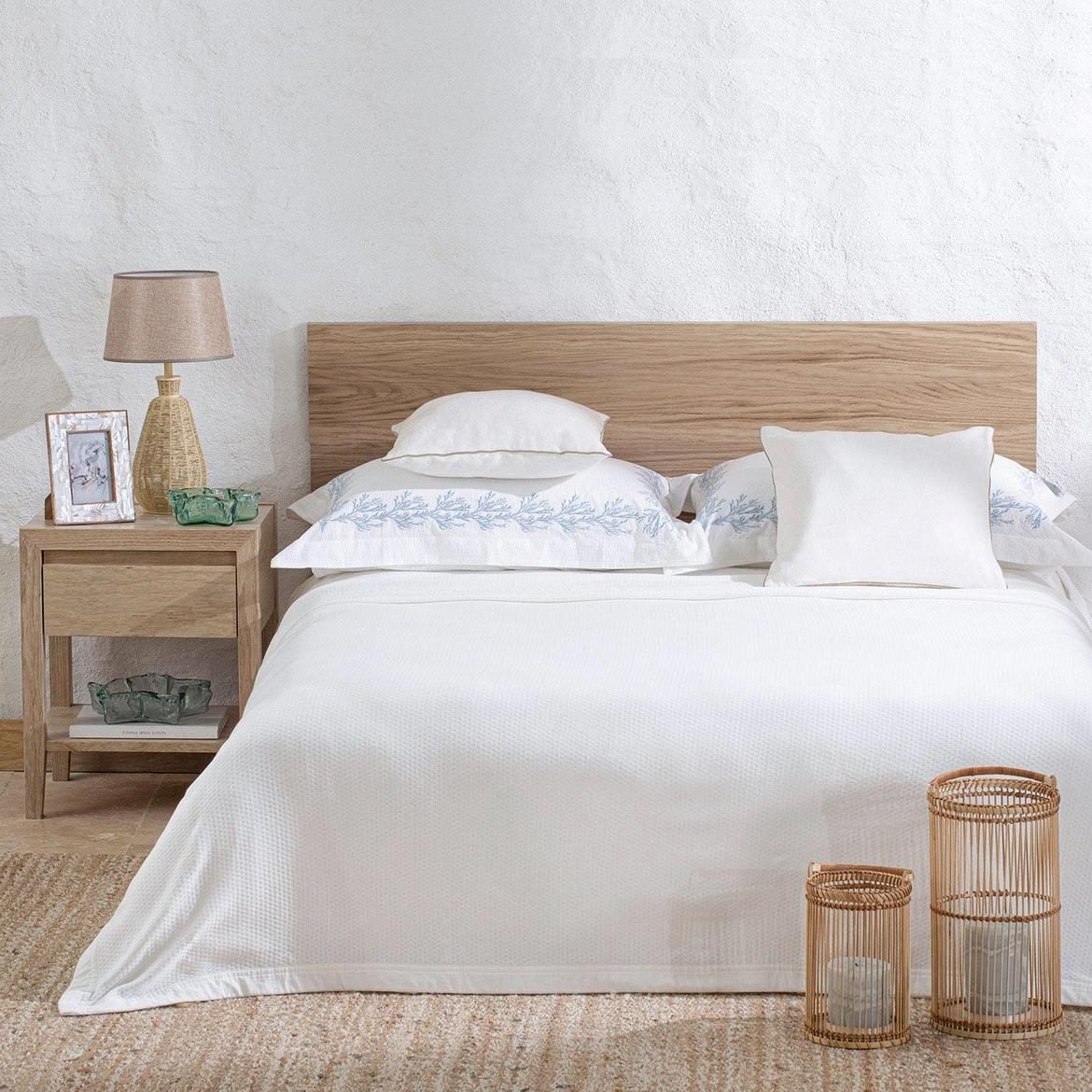 Bedroom with a timber headboard, white linen and a lamp on the bedside table