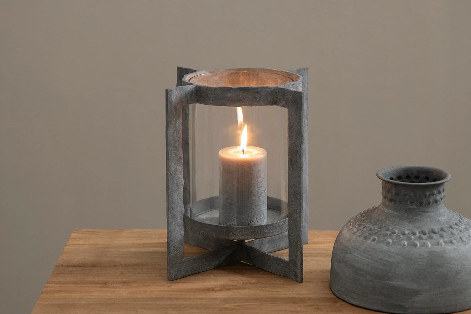 Candle lantern and a stone vase on a rustic wooden table
