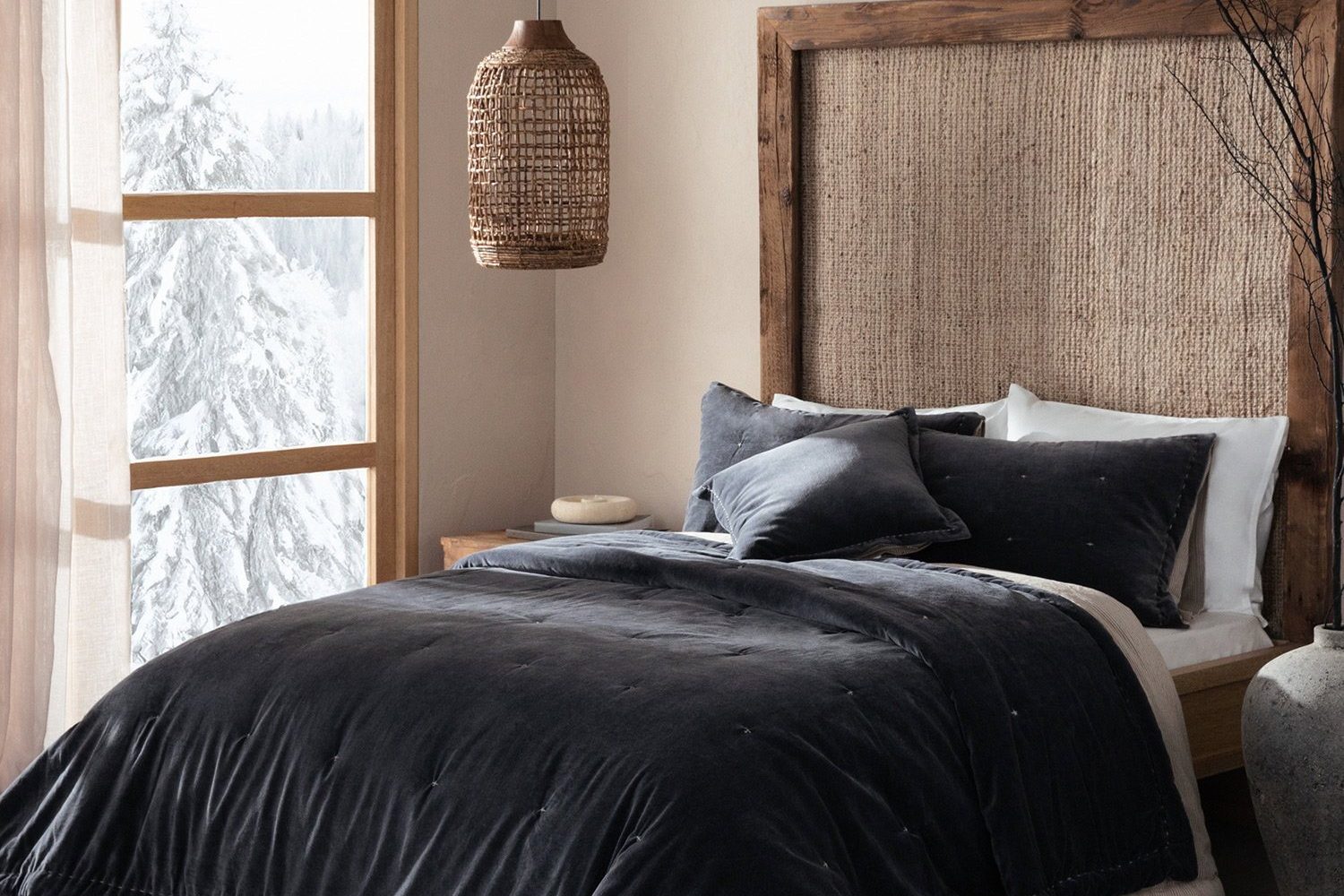 Bedroom with a dark velvet bedspread, a woven headboard and snow outside the window